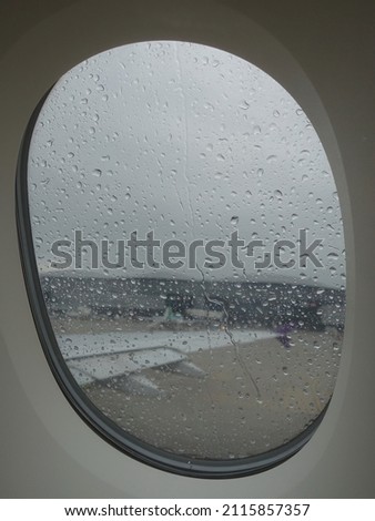 View through an Airplane Window on a Stormy Day with Close-up Focus on Rain Drops