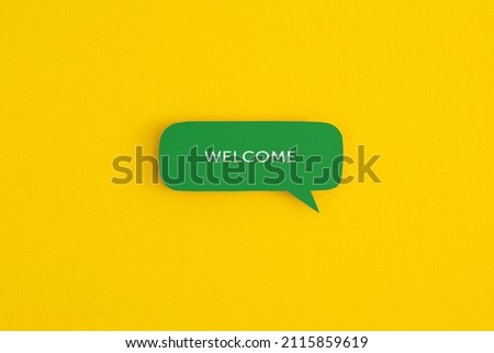 Paper speech bubble with the word "Welcome" on a yellow background. Top view with copy space. Flat lay.