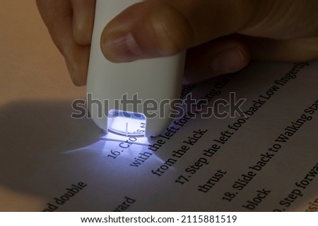 Kid's hand holding a reader and translator pen that scans English text and translates it in an instant.