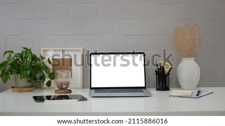 Creative workplace with laptop computer, houseplant, coffee cup and picture frame.