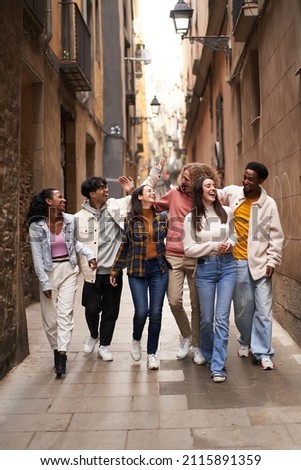 Vertical photo of a group of young happy friends walking in the street of the city. Smiling students laughing and having fun togethers Royalty-Free Stock Photo #2115891359