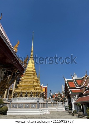 A Thai-style temple and Thai-style pavilion at the corner of the roof is a serpent king of nagas. There is a large yellow Thai pagoda with a patterned tile base and plant pots. The background is a blu