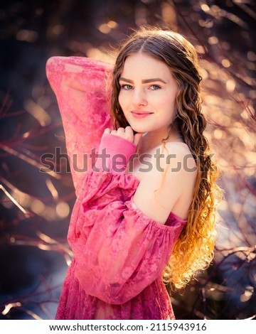 Beautiful image of a very pretty woman in a beam of sunlight and a pink dress