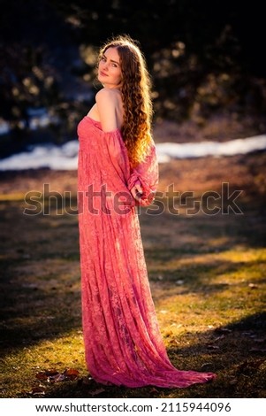 Beautiful image of a very pretty woman in a beam of sunlight and a pink dress