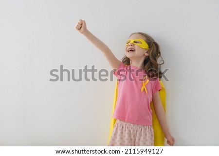 World Childhood cancer Day.  Girl in superhero costume with golden ribbon.  Royalty-Free Stock Photo #2115949127