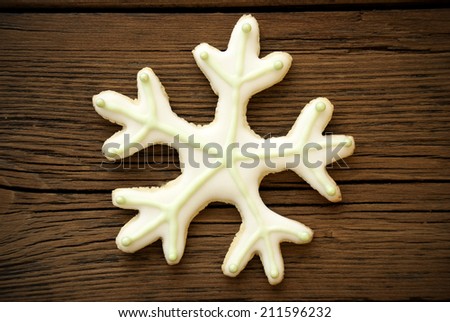 A Snowflake Cookie with white and green Icing on Wood