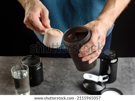 The athlete adds protein to the shaker. The concept of sports nutrition and supplements. Royalty-Free Stock Photo #2115965057