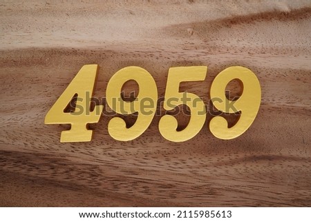 Wooden Arabic numerals 4959 painted in gold on a dark brown and white patterned plank background.