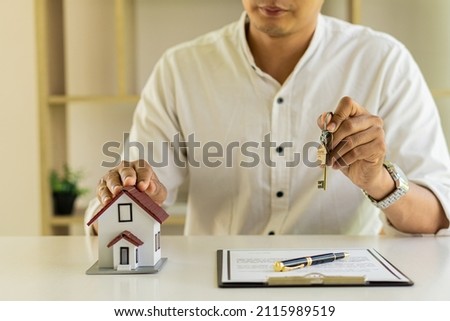 The real estate agent holds the house keys to his clients after signing the contract in the office. home loan concept Real estate, moving house or renting the property