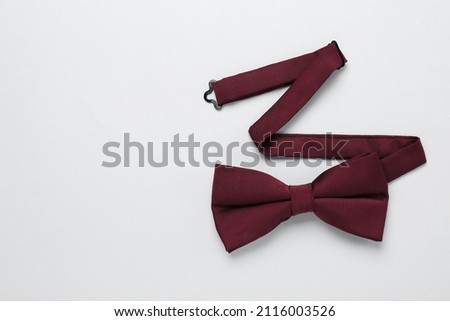Stylish burgundy bow tie on white background, top view. Space for text