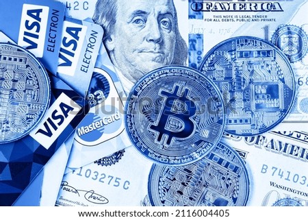 Bitcoin on the background of one hundred dollar bills and credit cards. Bitcoin is a convenient payment in the market of the global economy. A modern way to exchange bitcoin cash for dollars. Toned