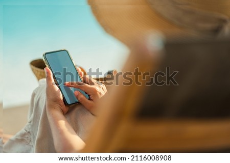 Young Asian woman using smartphone beside the pool at luxury hotel. technology and business concept background. Royalty-Free Stock Photo #2116008908