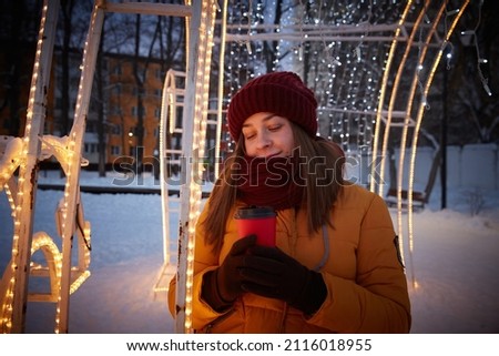 Evening walk of a young woman through a decorated city in winter