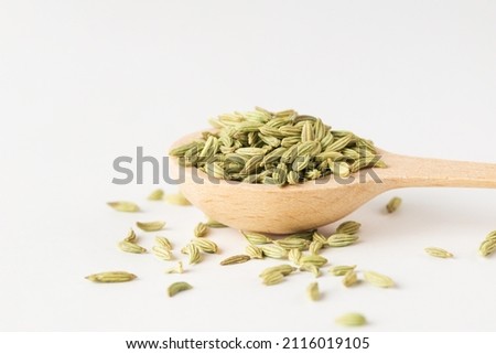 Macro photo of green dry fennel seeds in  wooden spoon on white background Royalty-Free Stock Photo #2116019105