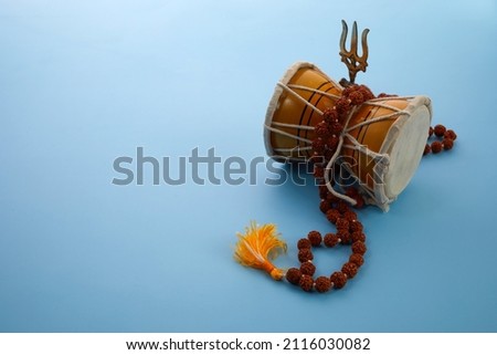 Shivaratri background with Shivas trident and Pellet Drum Damroo musical instrument . Hindu festival Maha Shivratri Royalty-Free Stock Photo #2116030082