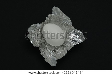 Chicken egg wrapped in foil on a dark background
