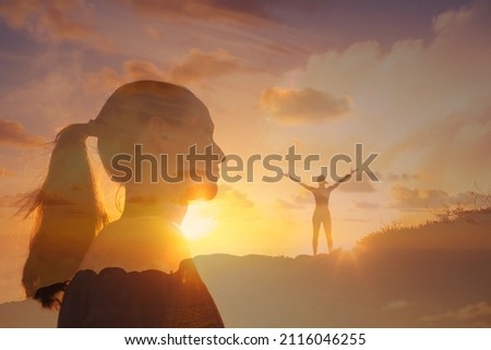 Happy young woman lifting her arms up standing onto mountain feeling inspired and positive. Finding freedom and hope concept.  Royalty-Free Stock Photo #2116046255