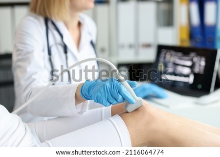 Doctor doing ultrasound examination of patient knee joint in clinic closeup Royalty-Free Stock Photo #2116064774