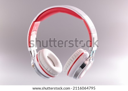 Closeup of red and white wireless headphones on gray background