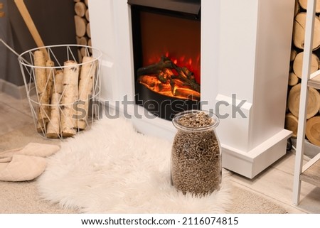 Basket and jar with firewood near mantelpiece in living room