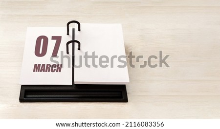 march 7. 7th day of month, calendar date. Stand for desktop calendar on beige wooden background. Concept of day of year, time planner, spring month.