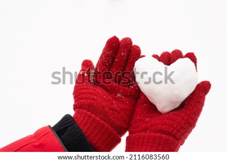 Close-up view stock photography of small white snow heart in hands of woman. Female hands in warm red gloves holding cute snowy heart. Love to winter season, St. Valentine's Day, Christmas concept Royalty-Free Stock Photo #2116083560