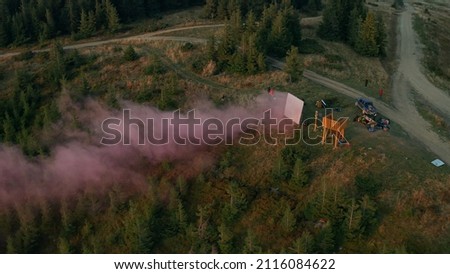 Mountain movie shooting team aerial view with smoke screen green trees growing. Drone scene group people filming process rocky woods hills campsite adventure. Outdoors nature activity concept