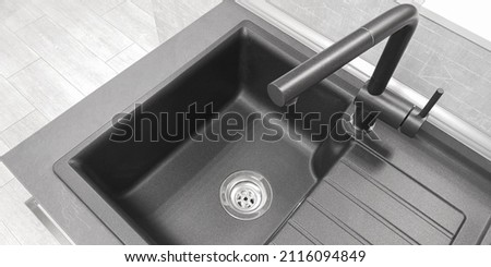 Close-up top view integrated single basin bowl sink with drainboard, dark color. Wing for drying utencil with grooves for draining water. Mixer tap of same material, neutral light kitchen background Royalty-Free Stock Photo #2116094849