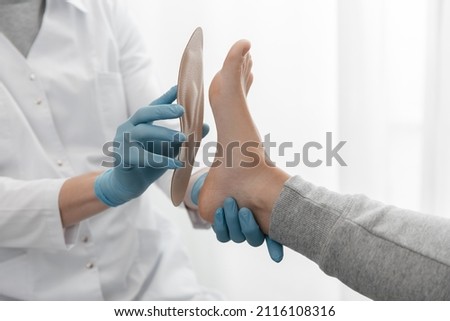 Doctor hands hold an orthopedic insole. Orthopedist tests the medical device. Orthopedic insoles on a white background. Foot care, comfort for the feet. Prevention of flat feet and foot diseases. Royalty-Free Stock Photo #2116108316