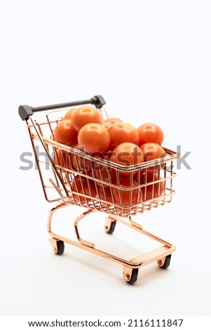 Mini shopping trolley with tomato on white background