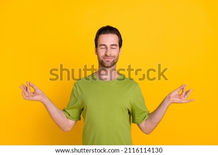 Photo of sleepy brunet hairdo millennial guy hold fingers wear green t-shirt isolated on vivid yellow color background