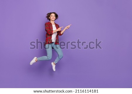 Full length photo of funny young brunette lady jump index promo wear shirt jeans sneakers isolated on purple background