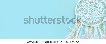 Image of white dream catcher over pastel blue background. Top view