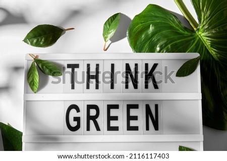sustainability, environment and ecology concept - close up of light box with go green words and monstera leaves on white background