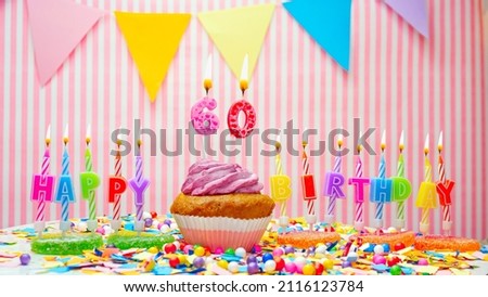 Happy birthday number 60. On a pink background, congratulations on the birthday of a sixty year old. Muffins with pink cream with a burning candle. Copy space