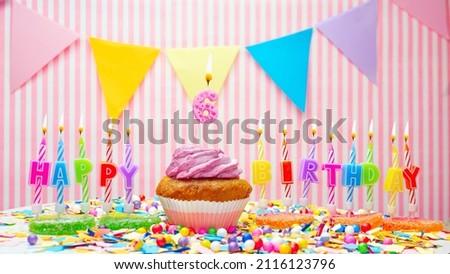 Happy birthday number 6. On a pink background, a happy birthday greeting for a six year old child. Muffins with pink cream with a burning candle. Copy space