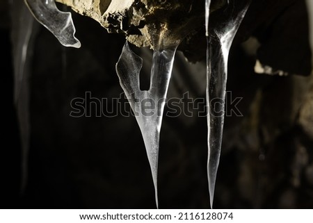 close up view on particular ice stalagmites inside a cave, dark abstract background