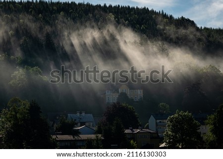 Sun shining through forest and mist in the morning in summer, Mariazell (Austria)