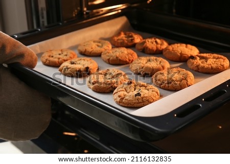 Baking tray with tasty homemade cookies taking out from oven Royalty-Free Stock Photo #2116132835