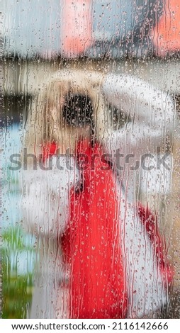 Rain. Girl photographed themselves with camera in street mirror with rain drops. Woman with camera