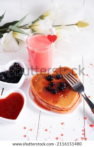 Red milkshake with pancakes in the form of a heart on a light background. Concept for Valentine's Day and Mother's Day
