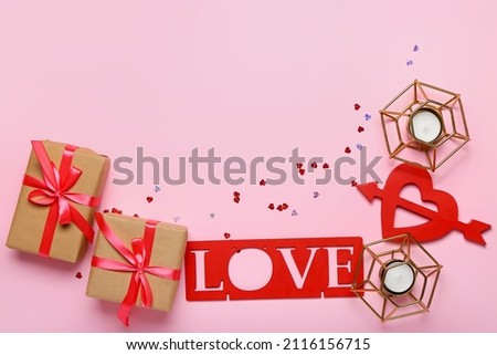 Valentine's Day gifts, word LOVE and candles on color background