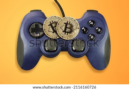 Crypto gaming concept. Video game controller with a bitcoin cryptocurrency coin on a background Royalty-Free Stock Photo #2116160726