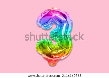 Rainbow foil balloon number, digit three on a pink background. Birthday greeting card with inscription 3. Top view. Numerical digit. Celebration event, template.