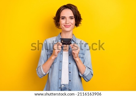 Photo of young pretty lady hold credit card income profit advertise promoter isolated over yellow color background