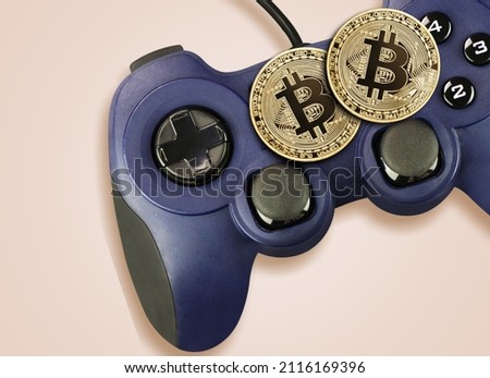 Crypto gaming concept. Video game controller with a bitcoin cryptocurrency coin on a background
