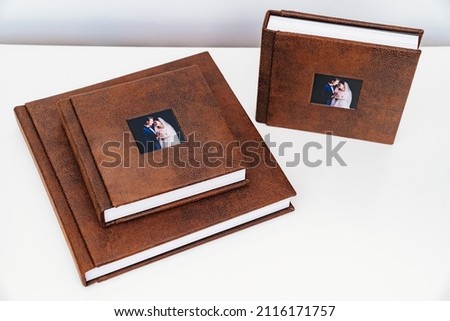 wedding photobooks in brown leather binding with photos on the cover. high-quality and expensive photo and printing products. services of a professional photographer and designer. on white background