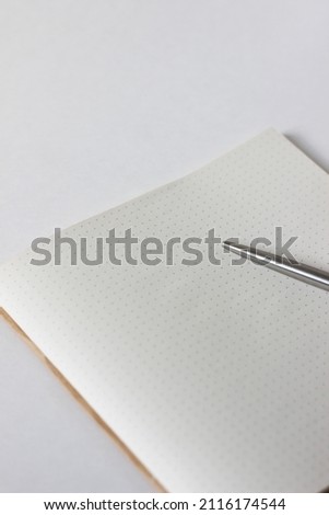 Open Notebook with Blank Dotted Sheet with Pen on White Desk. Minimal Mockup Template for Designer.