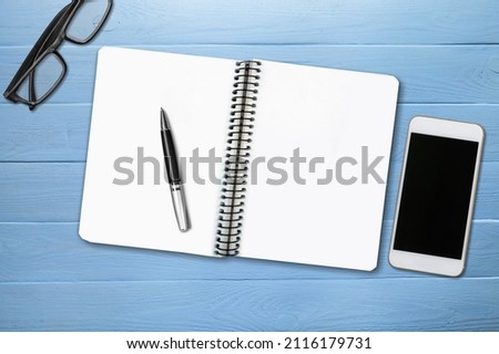 Desk with pen, glasses, smartphone and notebook