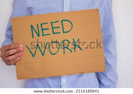 Unemployed man holding sign board with inscription NEED WORK. Concept of losing job and looking a new one. He is having financial problems and needs a job.